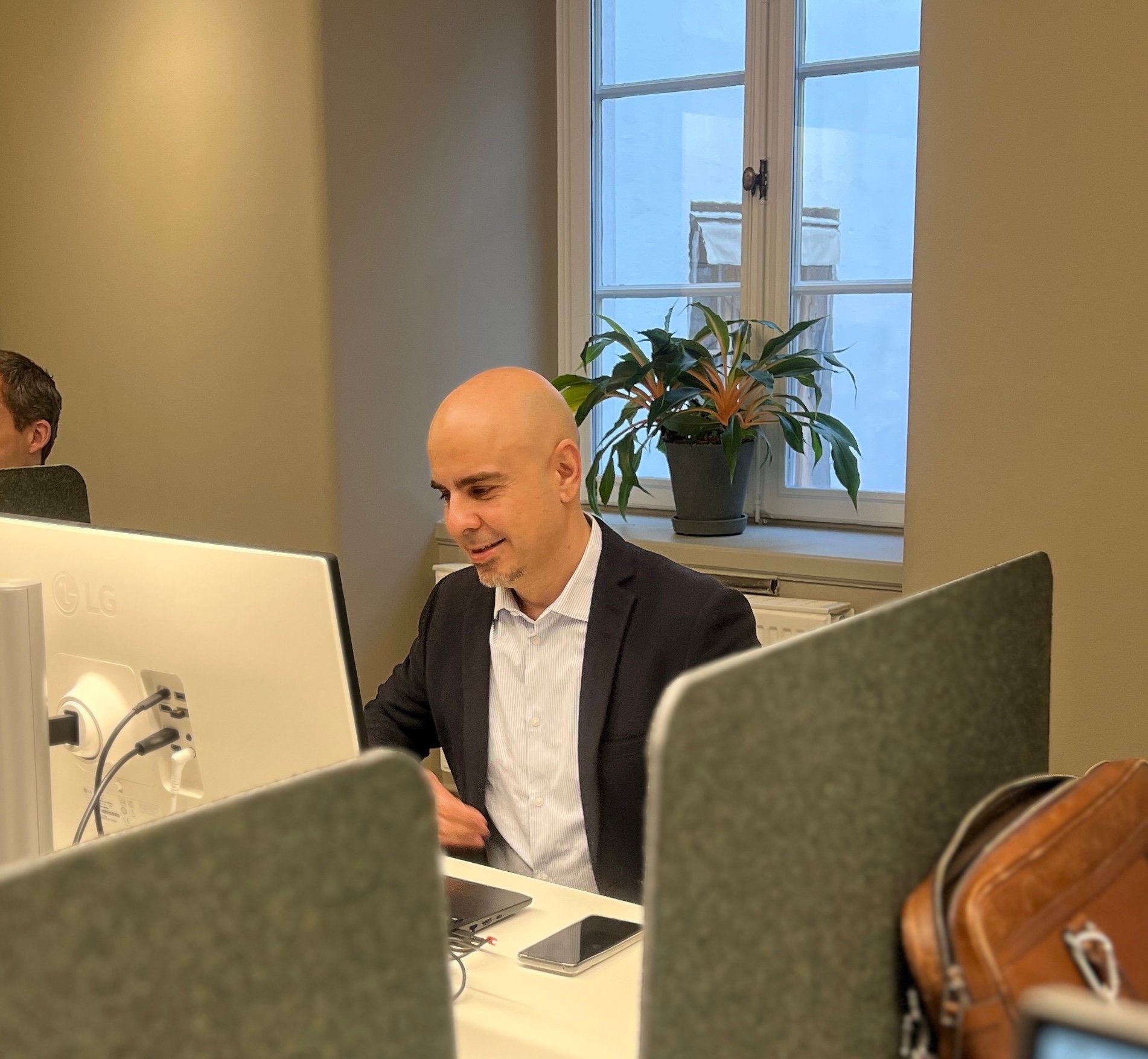 En man arbetar på en dator vid sitt skrivbord på ett kontor