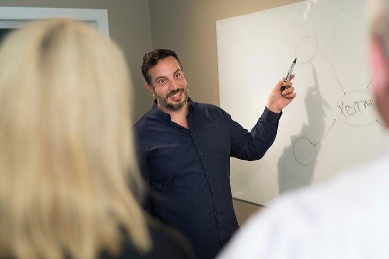 Manlig person står framför en whiteboard och pekar