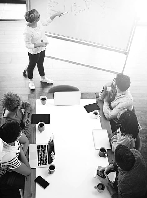 Consultant presents an AI testing concept to clients at a whiteboard in a modern meeting setting.