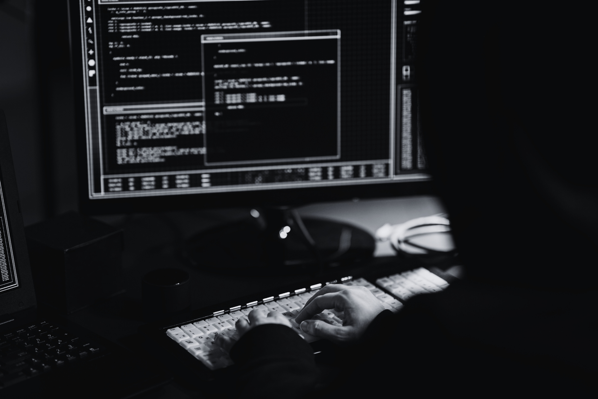 Black-and-white image of an IT specialist analyzing source code to protect against cyberattacks.